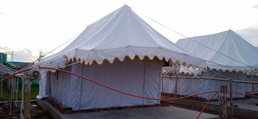 White Swiss cottage tents with frill, pitched on brick plinths
